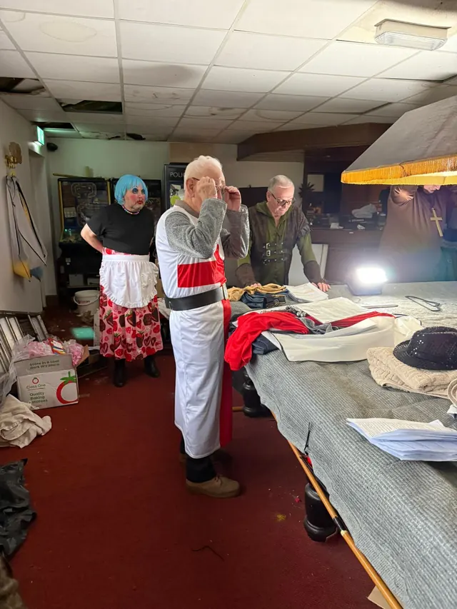Cast members preparing costumes backstage